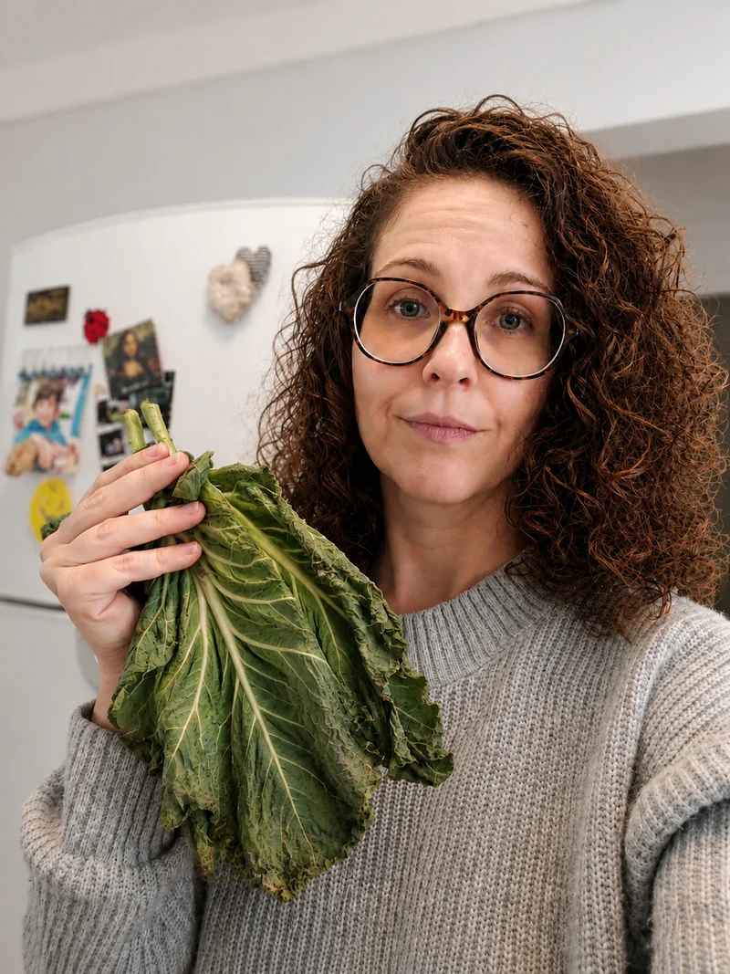 Pessoa em casa segurando folhas de couve levemente murchas diante da geladeira